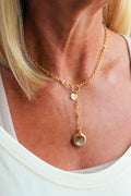 A woman wearing a Twisted Silver gold necklace with a stone pendant.