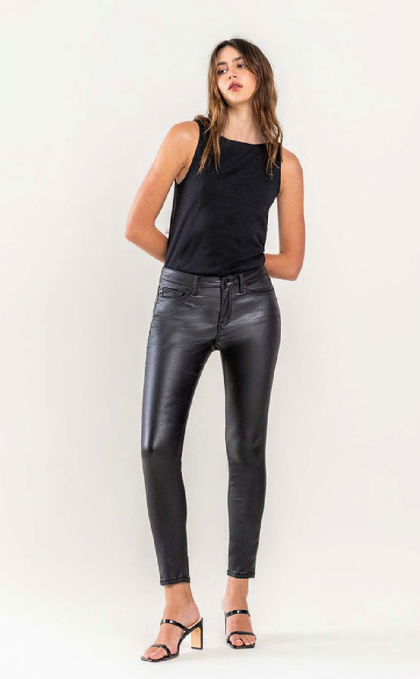 A model wearing black ankle faux leather skinny jeans and a black top.
