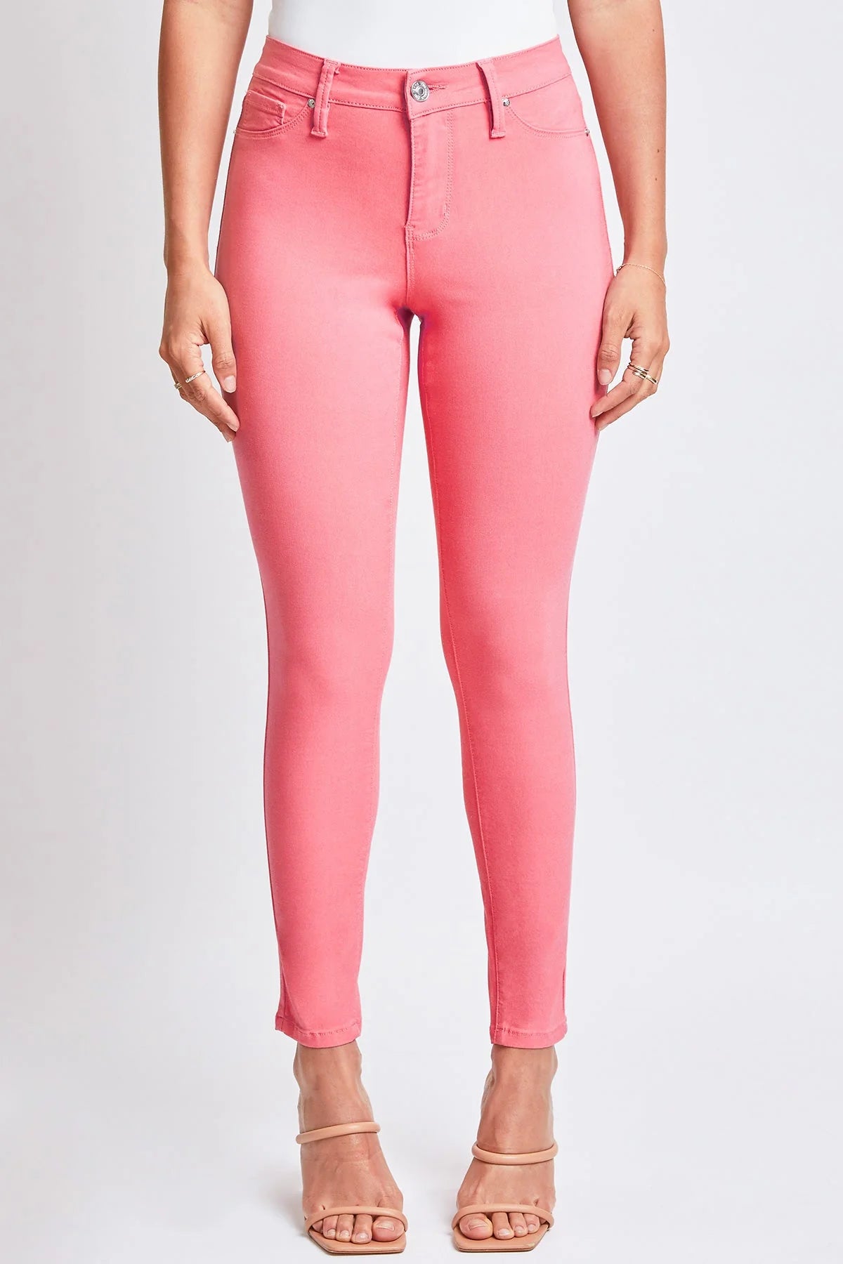 A pair of junior hyperstretch skinny pants in shell pink color, displayed on a model .