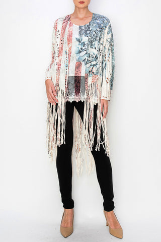 A model wearing a faux suede fringe jacket with a floral red, white and blue pattern. The jacket has long bell sleeves and fringe detailing at the hem.