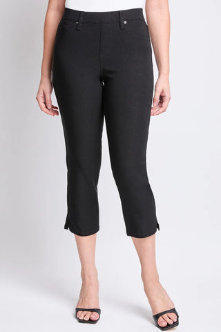 A pair of YMI junior hyperstretch pull-on capri pants in black with side slit, faux front pockets, and functioning back pockets.